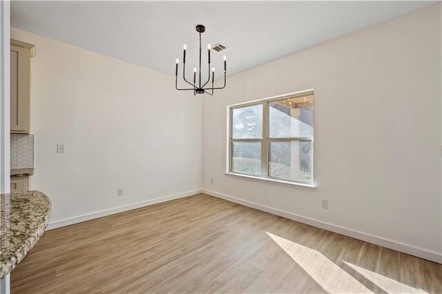 unfurnished dining area with light hardwood / wood-style floors and an inviting chandelier