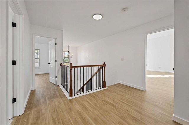 hallway with light hardwood / wood-style flooring and a chandelier