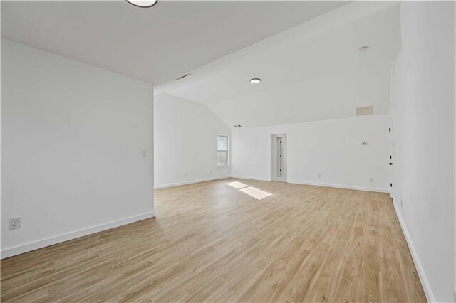 empty room with light hardwood / wood-style flooring and lofted ceiling