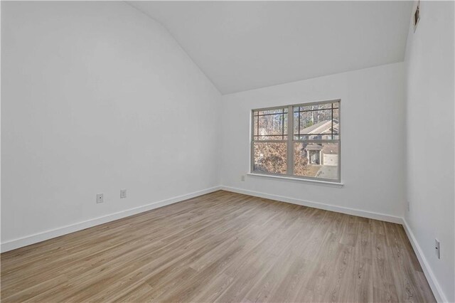 spare room with light hardwood / wood-style floors and vaulted ceiling