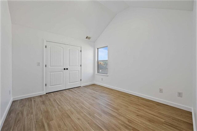 unfurnished bedroom featuring light hardwood / wood-style floors, a closet, and vaulted ceiling