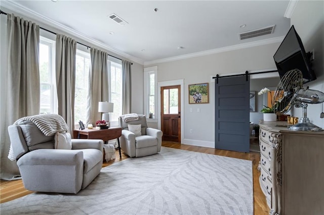 sitting room featuring ornamental molding, light wood-type flooring, visible vents, and a barn door