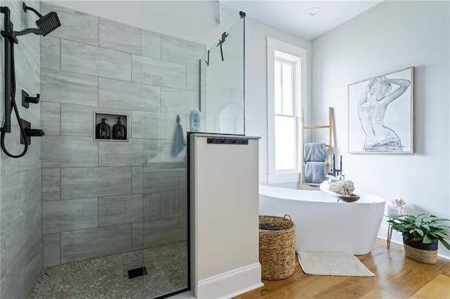 full bathroom featuring a freestanding bath, plenty of natural light, wood finished floors, and baseboards