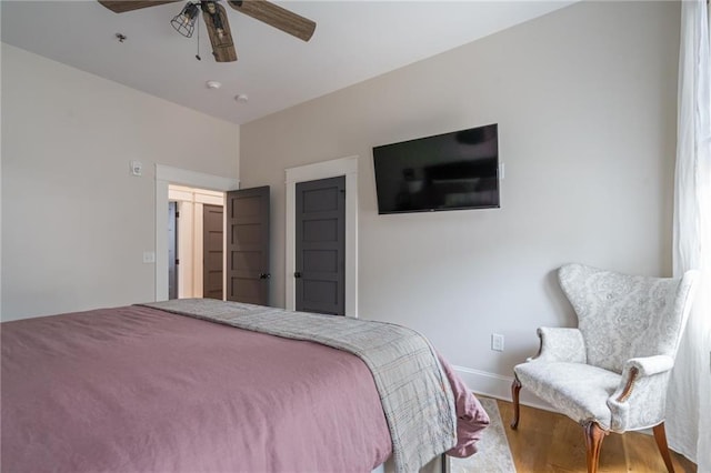 bedroom featuring wood finished floors, a ceiling fan, and baseboards