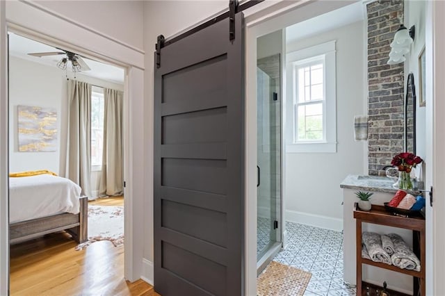 ensuite bathroom featuring a stall shower, baseboards, ceiling fan, and ensuite bath