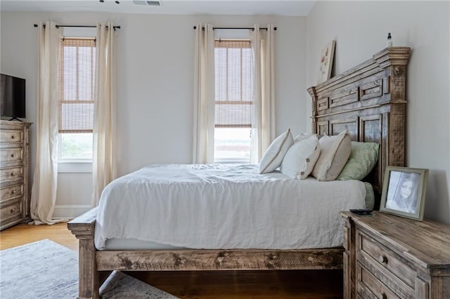 bedroom with light wood-style floors and visible vents