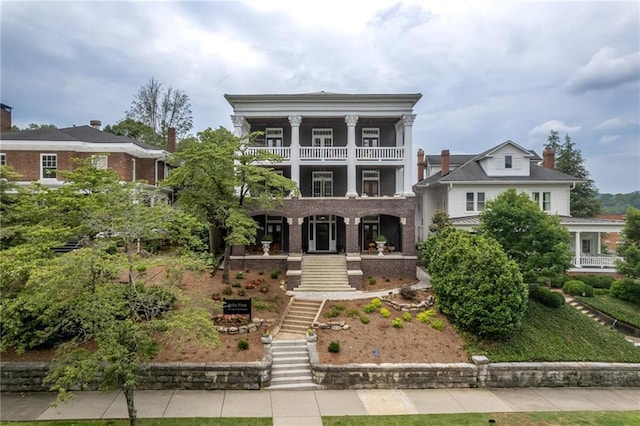 greek revival house featuring covered porch, stairway, and a balcony