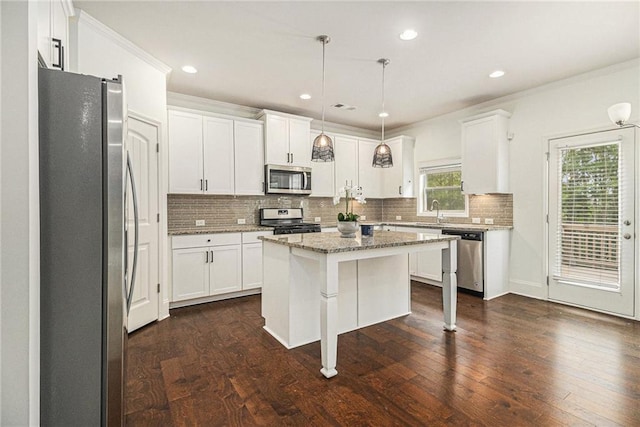 kitchen with a sink, stainless steel appliances, white cabinetry, tasteful backsplash, and a kitchen island