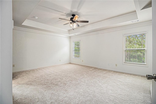carpeted empty room with crown molding, baseboards, ceiling fan, and a tray ceiling