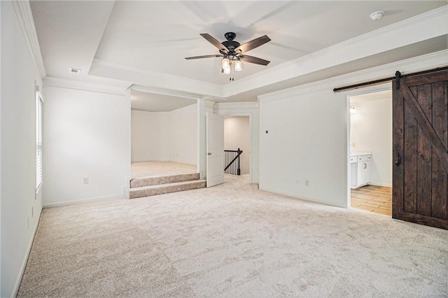 unfurnished bedroom with crown molding, a barn door, a raised ceiling, carpet, and baseboards
