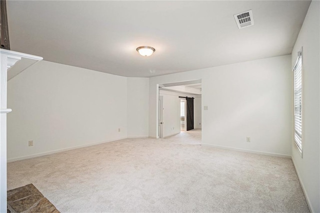 unfurnished room featuring visible vents, a wealth of natural light, and light carpet