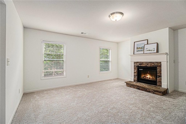 unfurnished living room with carpet floors, visible vents, plenty of natural light, and a fireplace