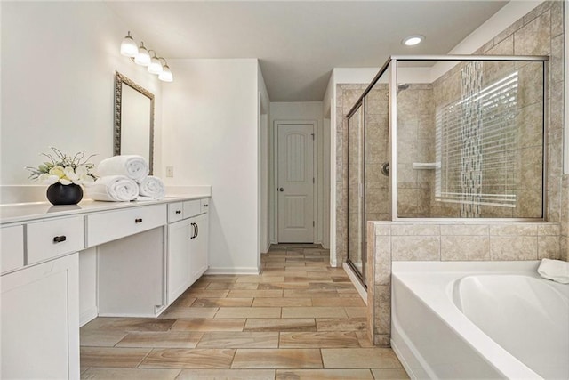 full bath with wood tiled floor, a bath, a stall shower, vanity, and recessed lighting