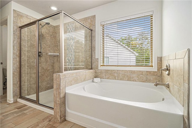 full bathroom featuring a garden tub, wood finished floors, toilet, recessed lighting, and a shower stall