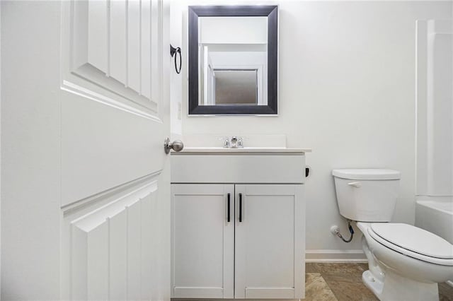 bathroom with vanity, baseboards, toilet, and a tub to relax in