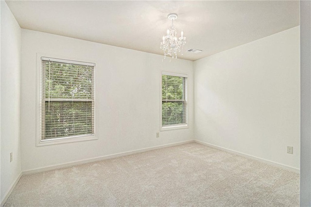 empty room with carpet flooring, baseboards, a chandelier, and visible vents