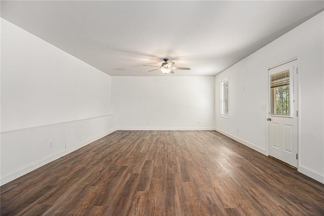 unfurnished living room featuring a ceiling fan, baseboards, and dark wood-type flooring