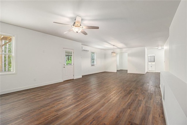 unfurnished living room featuring an AC wall unit, a ceiling fan, dark wood-style flooring, and baseboards