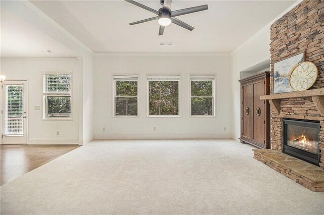 unfurnished living room with visible vents, light carpet, a stone fireplace, baseboards, and a ceiling fan