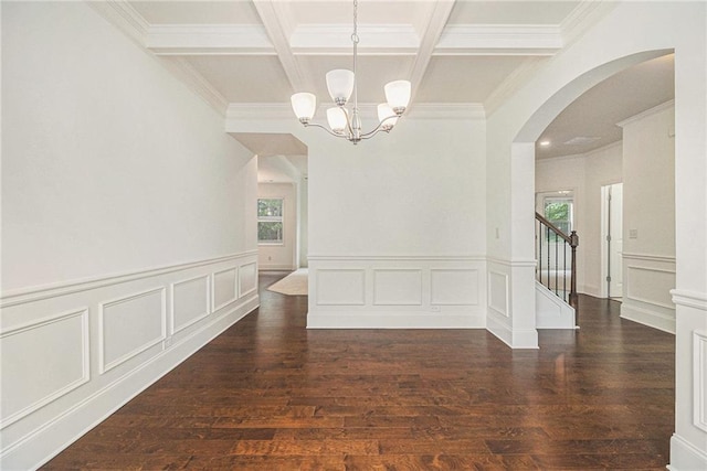 unfurnished dining area featuring arched walkways, a decorative wall, beam ceiling, an inviting chandelier, and coffered ceiling