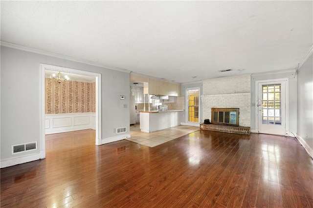 unfurnished living room with hardwood / wood-style flooring, a brick fireplace, and crown molding