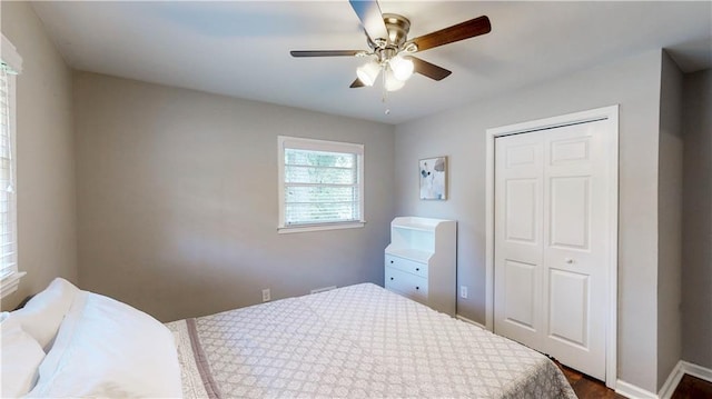 bedroom with dark hardwood / wood-style floors, a closet, and ceiling fan