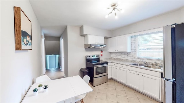 kitchen with stainless steel appliances, sink, light tile patterned flooring, white cabinetry, and tasteful backsplash