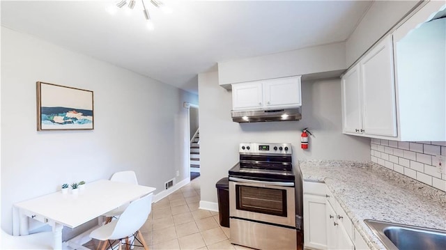 kitchen with tasteful backsplash, electric range, white cabinetry, light stone counters, and light tile patterned floors