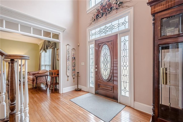 entrance foyer featuring light wood-style flooring, baseboards, and a towering ceiling