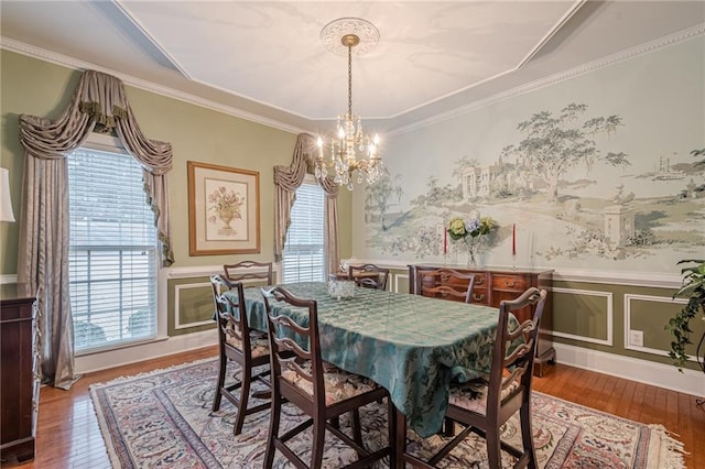 dining space featuring a chandelier, a wainscoted wall, crown molding, and hardwood / wood-style flooring