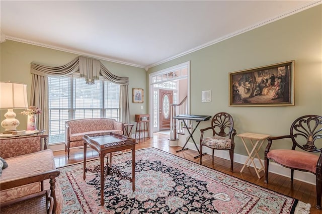 living room featuring baseboards, wood-type flooring, and ornamental molding