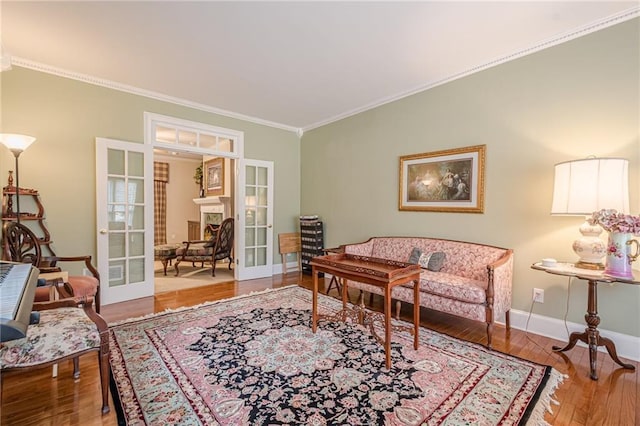 sitting room with wood finished floors, crown molding, french doors, and baseboards