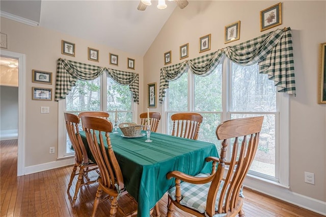 dining area featuring baseboards, high vaulted ceiling, a healthy amount of sunlight, and hardwood / wood-style floors