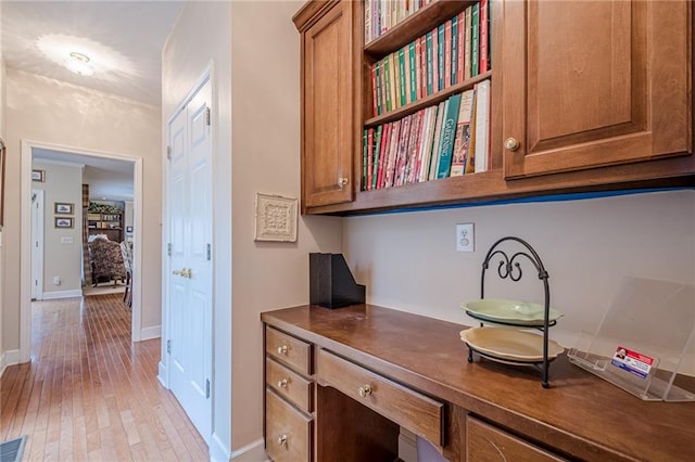 interior space featuring visible vents, brown cabinets, light wood-style flooring, dark countertops, and baseboards