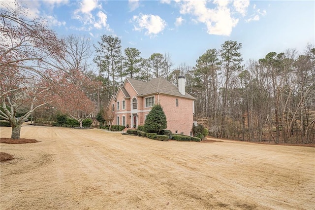 view of side of property with a lawn, brick siding, and a chimney