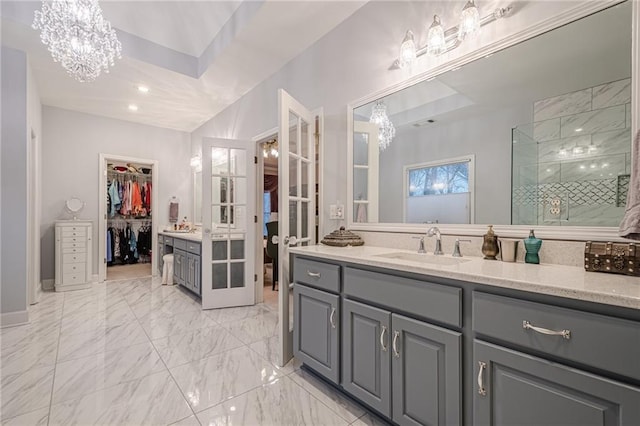 full bath with vanity, an inviting chandelier, a stall shower, a walk in closet, and marble finish floor