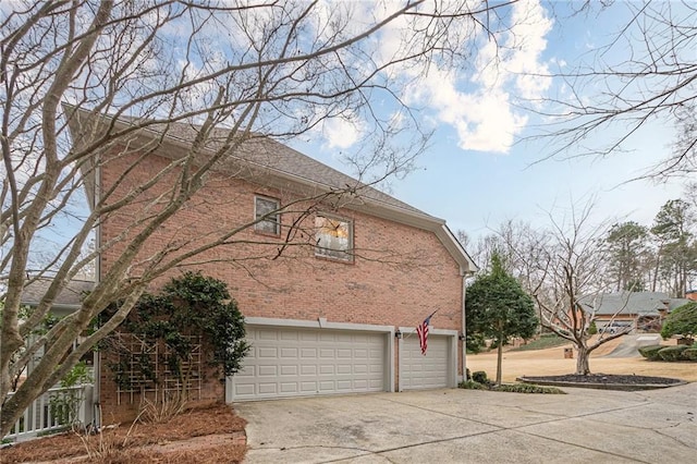 view of side of home featuring a garage, brick siding, and driveway