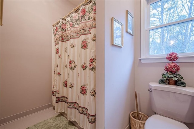 bathroom featuring tile patterned floors, baseboards, toilet, and a healthy amount of sunlight