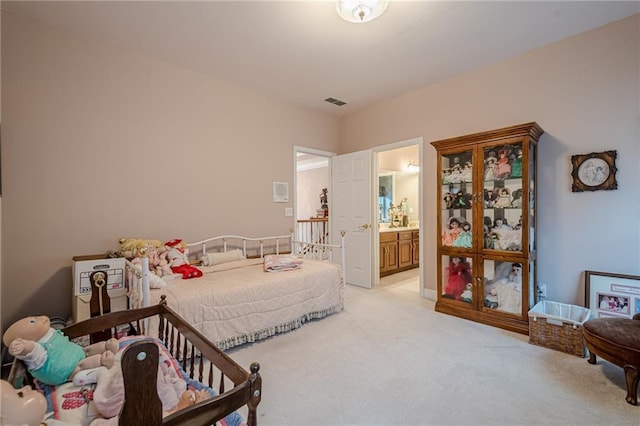 bedroom featuring connected bathroom and light carpet