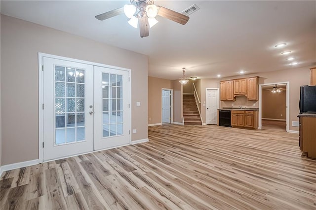 unfurnished living room featuring visible vents, french doors, light wood finished floors, baseboards, and stairs