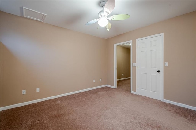 empty room with ceiling fan, attic access, baseboards, and light carpet