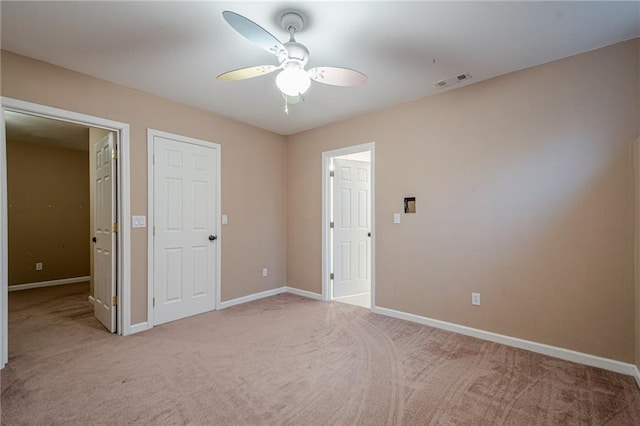 unfurnished bedroom featuring ceiling fan, light colored carpet, visible vents, and baseboards