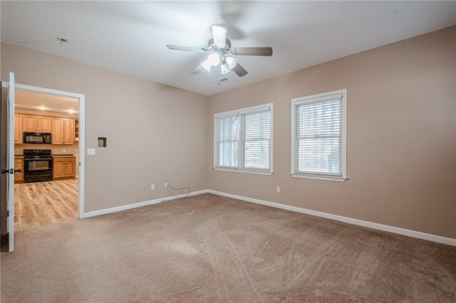 empty room with light colored carpet, a ceiling fan, and baseboards