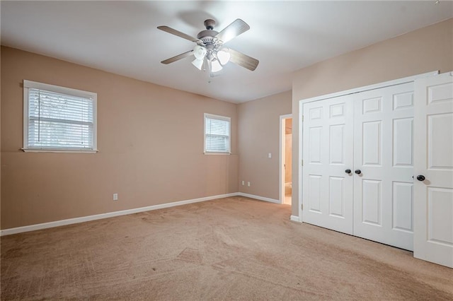 unfurnished bedroom with ceiling fan, baseboards, a closet, and light carpet