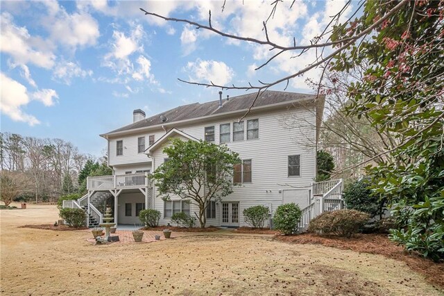 rear view of house with stairs, french doors, and a chimney