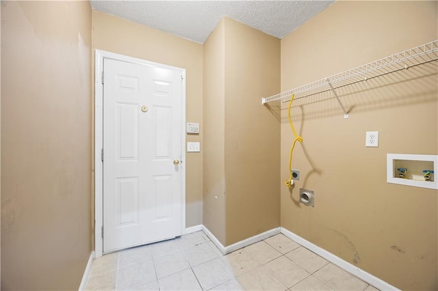 laundry room featuring electric dryer hookup, hookup for a washing machine, light tile patterned floors, and a textured ceiling