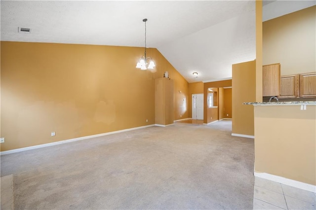 empty room with light colored carpet, lofted ceiling, and a chandelier