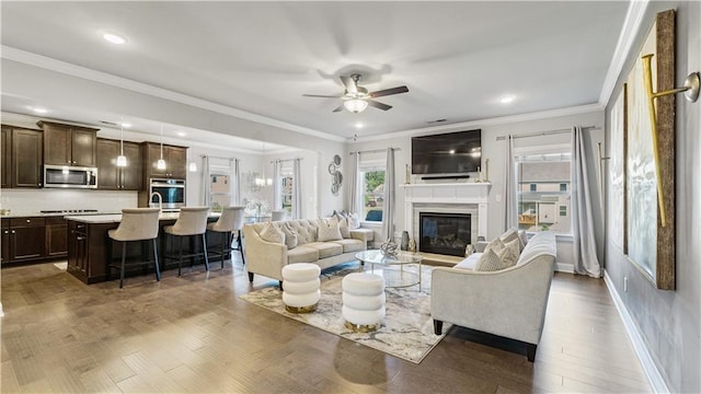 living room featuring ceiling fan, crown molding, a wealth of natural light, and dark hardwood / wood-style flooring