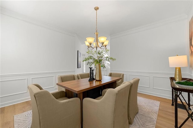 325 Cranbrooke Cir, Suwanee, GA 30024 - dining space with a chandelier, a decorative wall, crown molding, wainscoting, and light wood-style floors