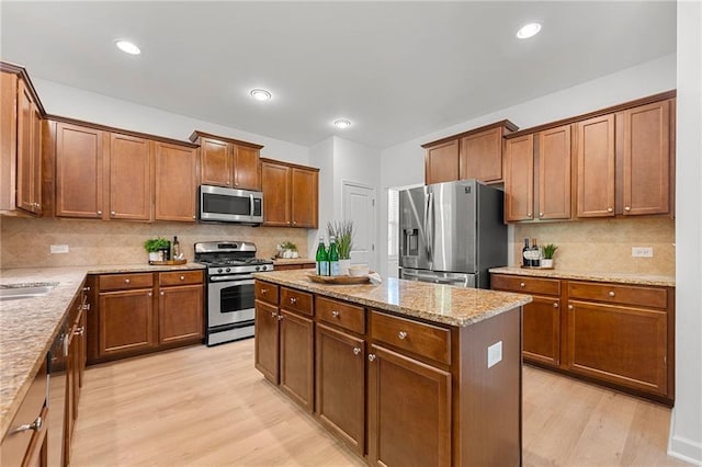 325 Cranbrooke Cir, Suwanee, GA 30024 - kitchen featuring appliances with stainless steel finishes, light wood finished floors, a kitchen island, decorative backsplash, and light stone counters